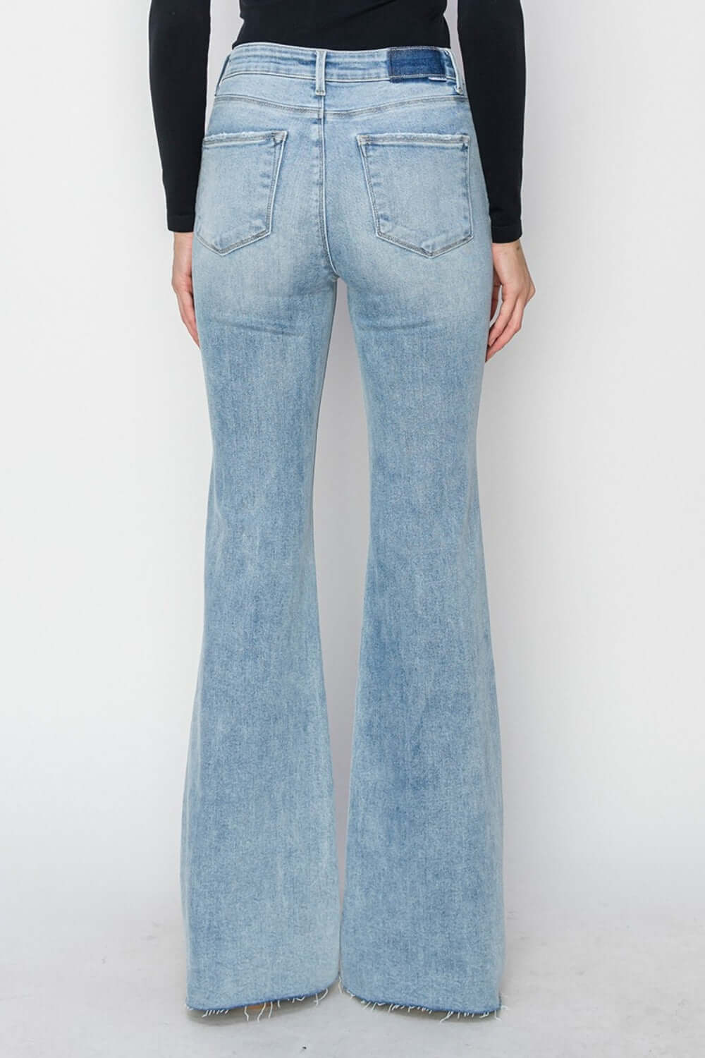 Back view of high rise raw cut hem bootcut jeans by Risen Jeans featuring a flattering fit and trendy raw cut hem detailing.