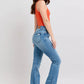 Model wearing high waist tummy control vintage wash slim boot jeans with side slits and an orange top.