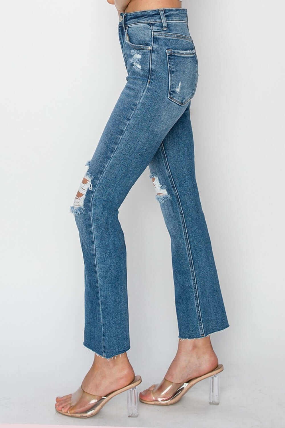 Trendy high rise distressed ankle jeans by Risen Jeans, paired with clear heels, showcasing flattering fit and versatile style