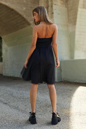 Woman wearing black mesh ruffle tube top swing dress standing under bridge, showcasing stylish and comfortable summer fashion.