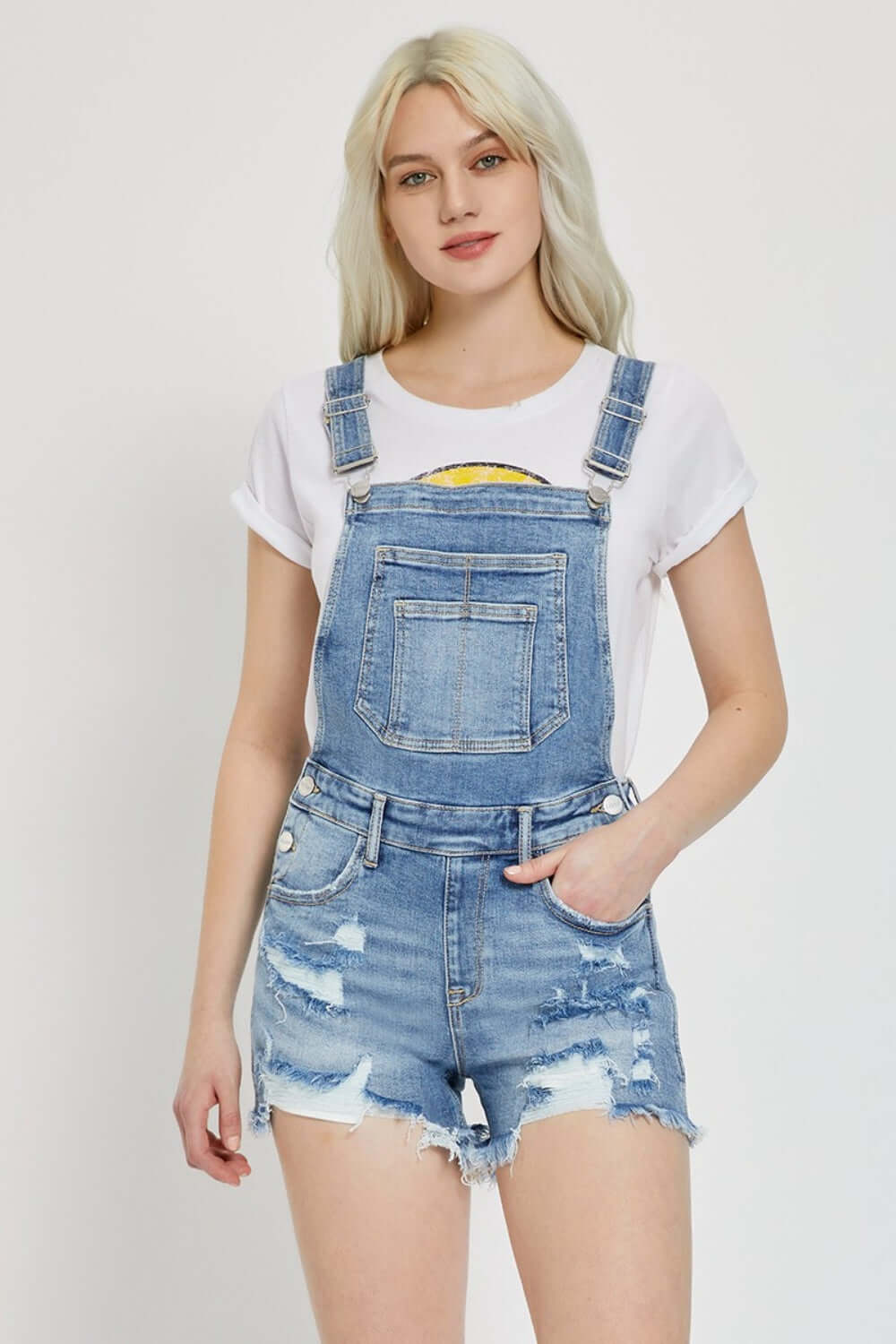 Woman wearing RISEN Distressed Raw Hem Denim Overalls with a white t-shirt, showcasing trendy casual Risen Jeans style