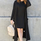 Woman wearing black open front long sleeve cover up with pockets, styled with black dress, white sneakers, sunglasses, and beige backpack.