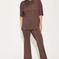 Woman wearing a bamboo drop shoulder t-shirt and flare pants set in brown, featuring a relaxed fit and paired with blue platform sandals.