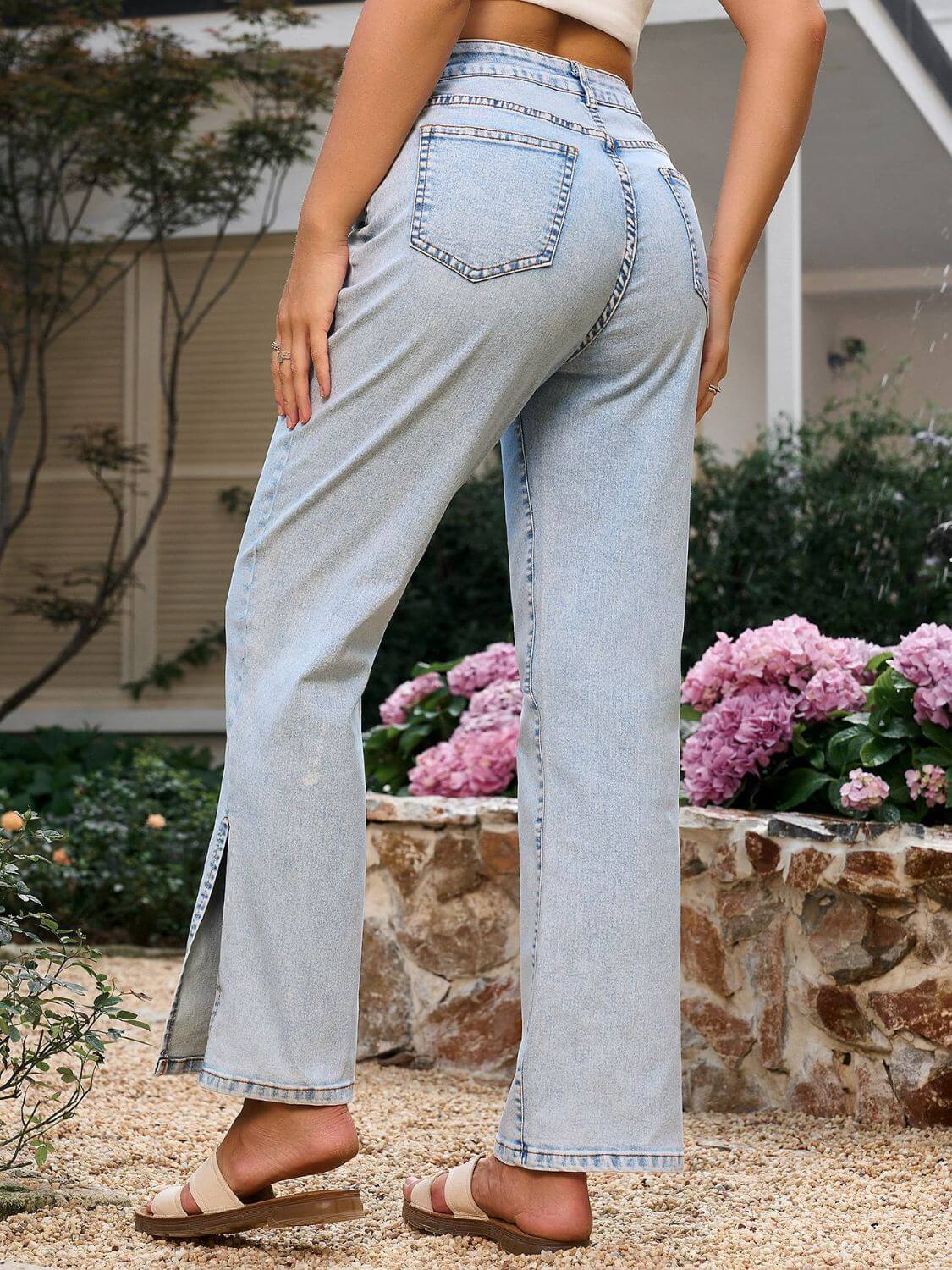 Stylish woman wearing Bella Road Side Slit Straight Leg Jeans with pockets, showcasing the back and side slit detail in a floral garden.