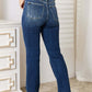 Back view of woman wearing Judy Blue Mid Rise Hand Sand & Destroy Bootcut Jeans Petite, showcasing fit and distressed details