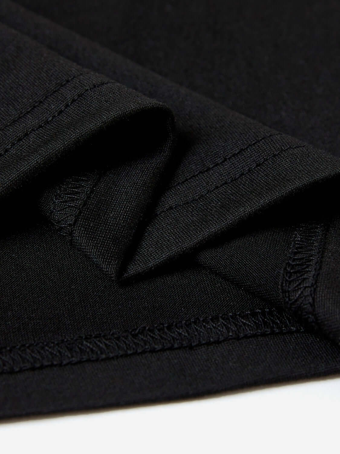 Close-up of black graphic round neck short sleeve T-shirt fabric displaying slightly stretchy and opaque polyester material.