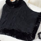 Bella Road black fuzzy hem cable-knit poncho draped over a chair, showcasing cozy winter style and texture.