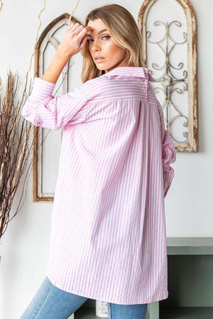 Woman wearing First Love Full Size Striped Button Down High-Low Hem Shirt in light pink and white stripes, standing indoors