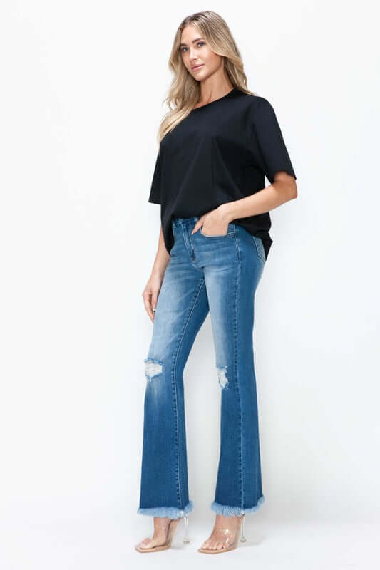 Model showcasing bytos Full Size Raw Hem Distressed High Rise Bootcut Jeans with a trendy black top. Perfect for casual or dressy looks!