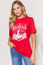 Woman wearing red graphic round neck short sleeve t-shirt with "Nashville Country Music" print.