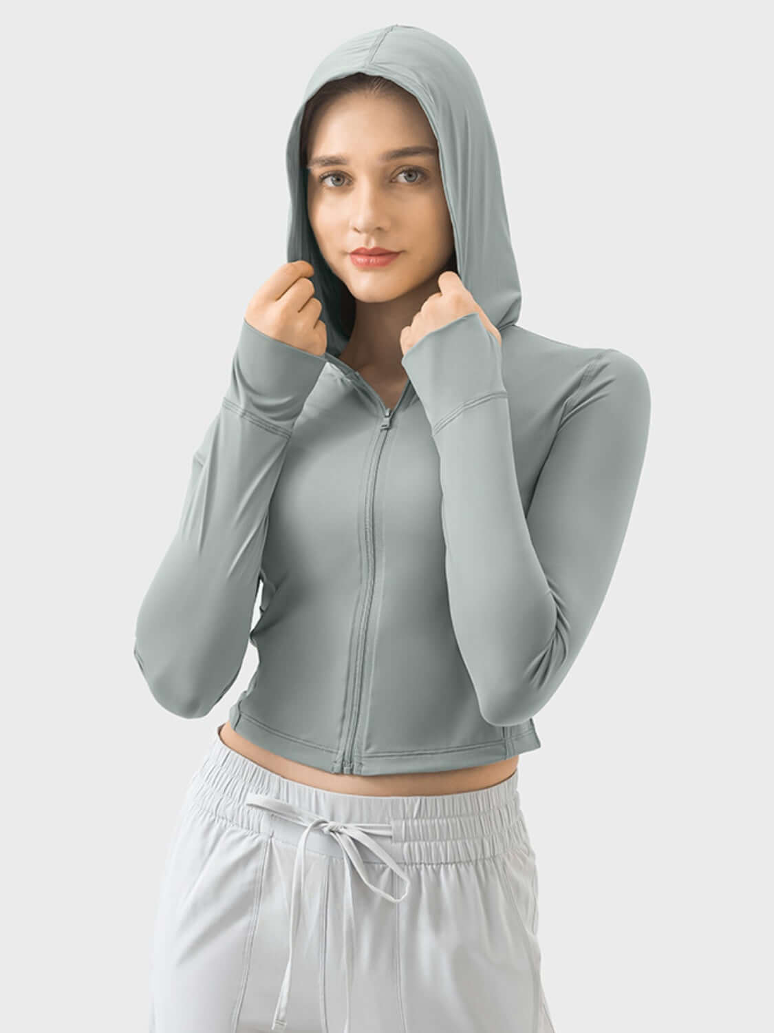 Woman in light green zip-up hooded active outerwear, showcasing style and comfort for an active lifestyle.