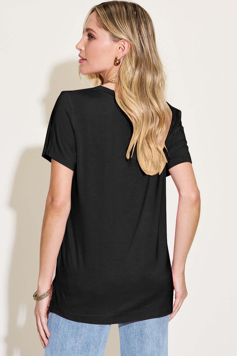 Woman wearing black Bamboo V-Neck High-Low T-Shirt, back view showing casual fit and short sleeves.