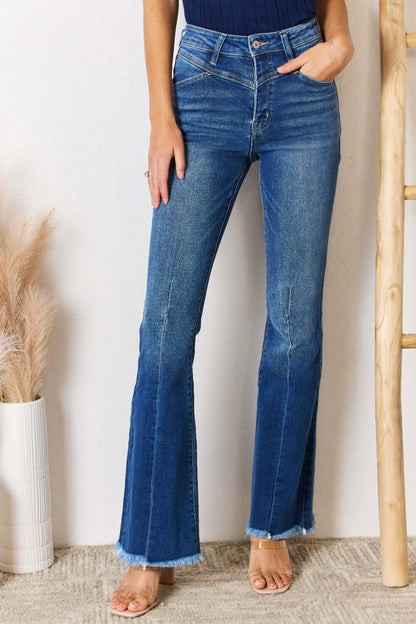 Woman wearing Kancan High Rise Raw Hem Flare Jeans with frayed edges, showcasing the flattering fit and chic retro design with intricate seam details