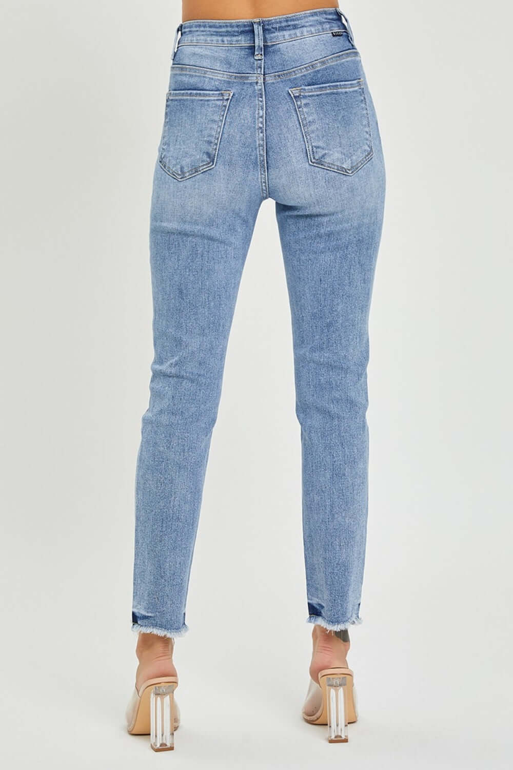 Back view of high rise frayed hem skinny jeans by Risen Jeans, showcasing trendy and flattering silhouette with frayed hem detail.