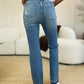 Back view of model wearing Mid Rise Destroyed Hem Distressed Jeans by Judy Blue, showcasing distressed detailing and comfortable mid-rise fit.