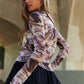 Woman wearing J.NNA marble design long sleeve mesh top, showcasing unique pattern and style under a bridge.