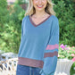 Trendy woman in a color block V-neck cropped sweatshirt, perfect for a stylish and sporty look with high-waisted jeans.