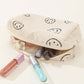 Smiley face corduroy cosmetic pouch with makeup products spilling out, adding a cheerful touch to beauty organization.