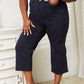 Woman wearing high waist tummy control wide cropped Judy Blue jeans in garment-dyed finish standing indoors.