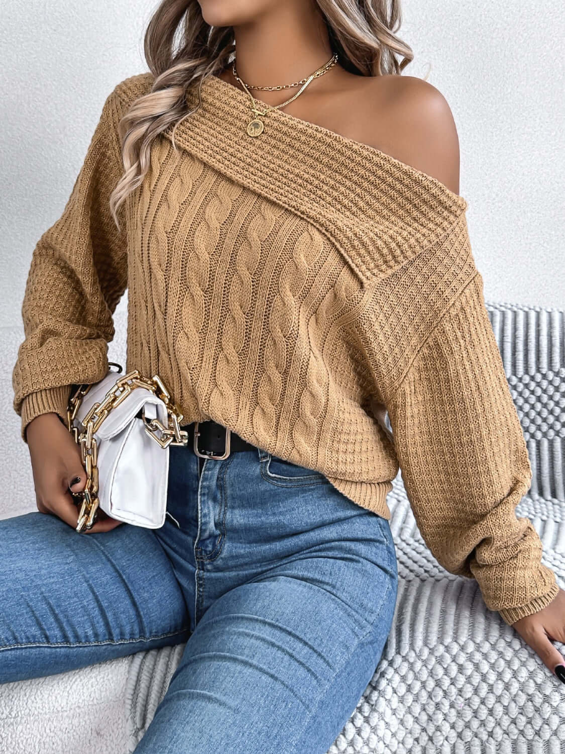 Woman wearing Bella Road Cable-Knit One Shoulder Long Sleeve Sweater styled with jeans and handbag