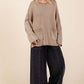 Mineral wash sweater with patch pockets and cut edges, worn with wide-leg jeans for a trendy casual look.