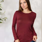 Woman wearing a drawstring round neck long sleeve top in burgundy, paired with blue jeans, showcasing its comfortable and stylish fit