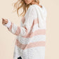 Woman wearing Reborn J high-low striped popcorn hoodie sweater with adjustable drawstrings in cozy, textured knit.