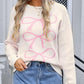 Woman wearing angel wings bow graphic cream round neck long sleeve sweater paired with denim skirt.