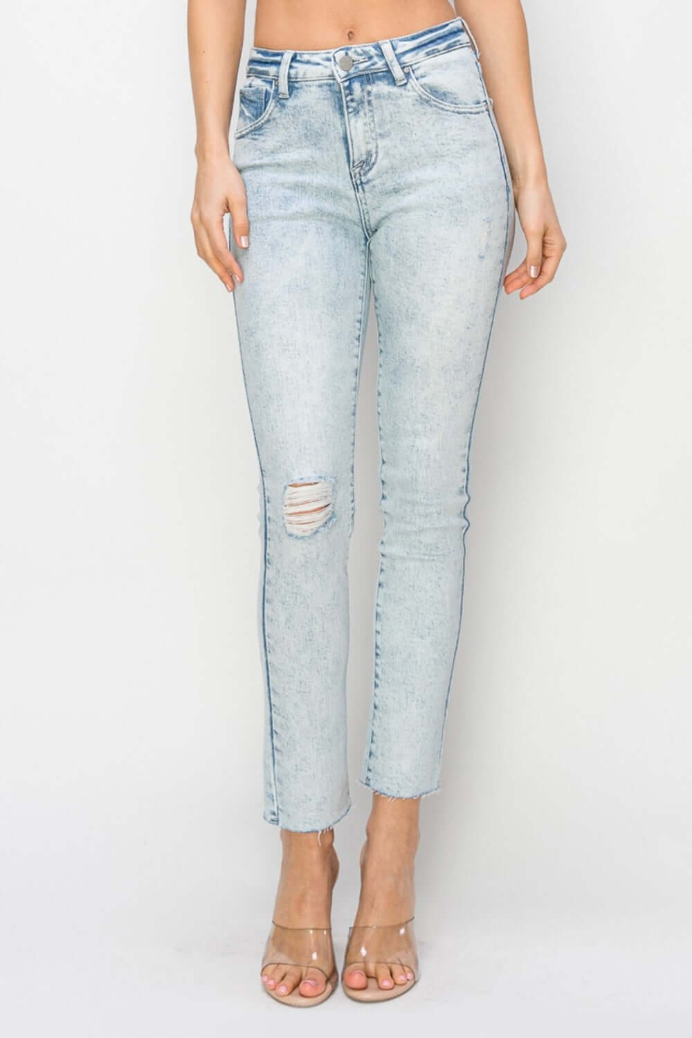 Woman wearing high rise distressed skinny Risen Jeans with a figure-flattering silhouette, featuring trendy distressed details and high rise design.