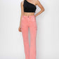 Model wearing high-rise side slit cargo bootcut jeans in pink paired with a one-shoulder black top, showcasing edgy and versatile style by Risen Jeans