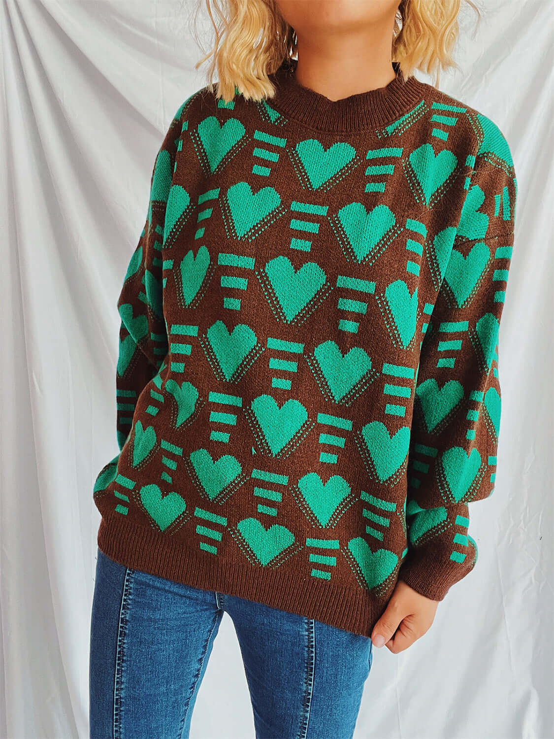 "Bella Road Heart Contrast Long Sleeve Dropped Shoulder Sweater in green and brown worn with blue jeans"