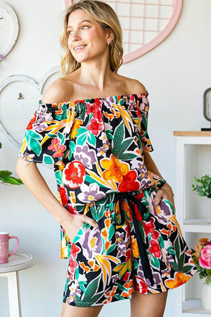 Woman wearing floral off-shoulder top with colorful floral pattern, perfect for warm weather outings and casual events.