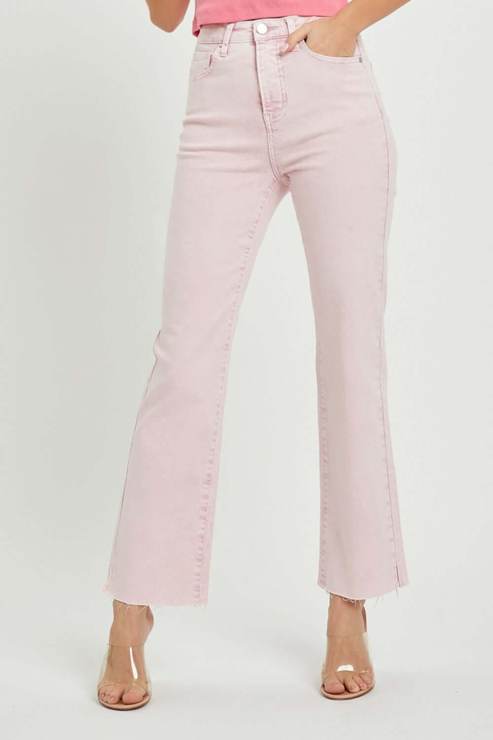 Woman wearing RISEN Full Size High Rise Tummy Control Straight Jeans with raw hem detail in a light pink color.