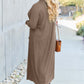 Woman wearing a brown open front long sleeve cover up with a pocket, styled with blue jeans and sunglasses, walking on a sidewalk.