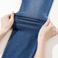 Demonstrating the moderate stretch of high waist skinny jeans in blue fabric.