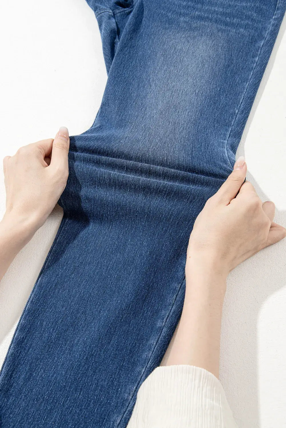 Demonstrating the moderate stretch of high waist skinny jeans in blue fabric.