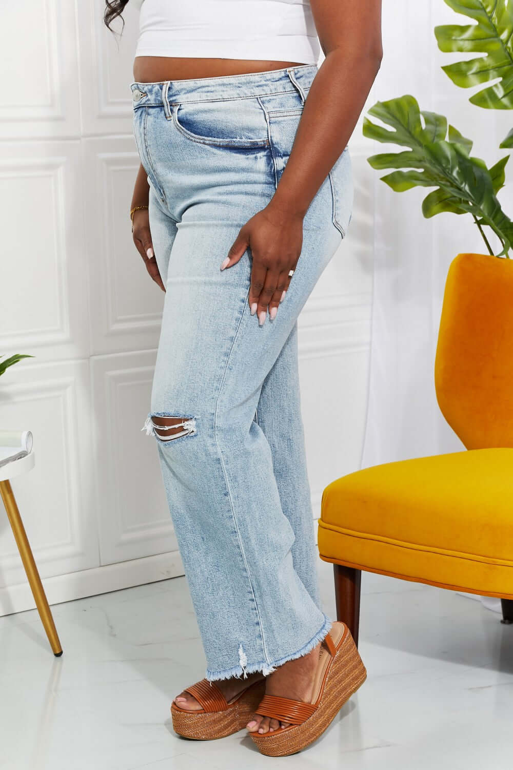 Light wash high waist distressed 90's dad jeans with raw hem and cat's whiskers fading, styled with platform sandals.