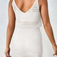 Back view of woman wearing white openwork V-neck sleeveless cover up dress made of stretchy sheer acrylic material.