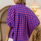 Woman wearing a plaid button-up dolman sleeve shirt with a relaxed fit, showcasing the versatile and stylish back view.