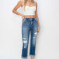 Woman wearing RISEN full size cuffed ankle distressed straight jeans with a white crop top and clear heels.