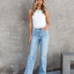 Woman wearing Washed Straight Leg Jeans with a white top, standing against a concrete wall.