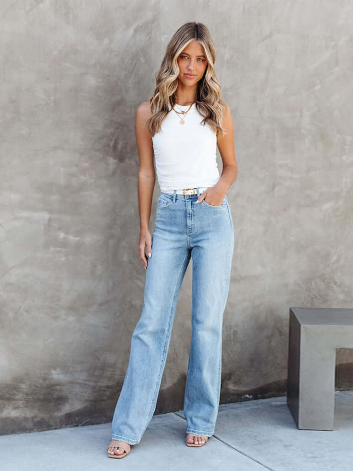 Woman wearing Washed Straight Leg Jeans with a white top, standing against a concrete wall.