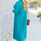 Woman wearing turquoise open front long sleeve cover up with pockets, walking on a sidewalk