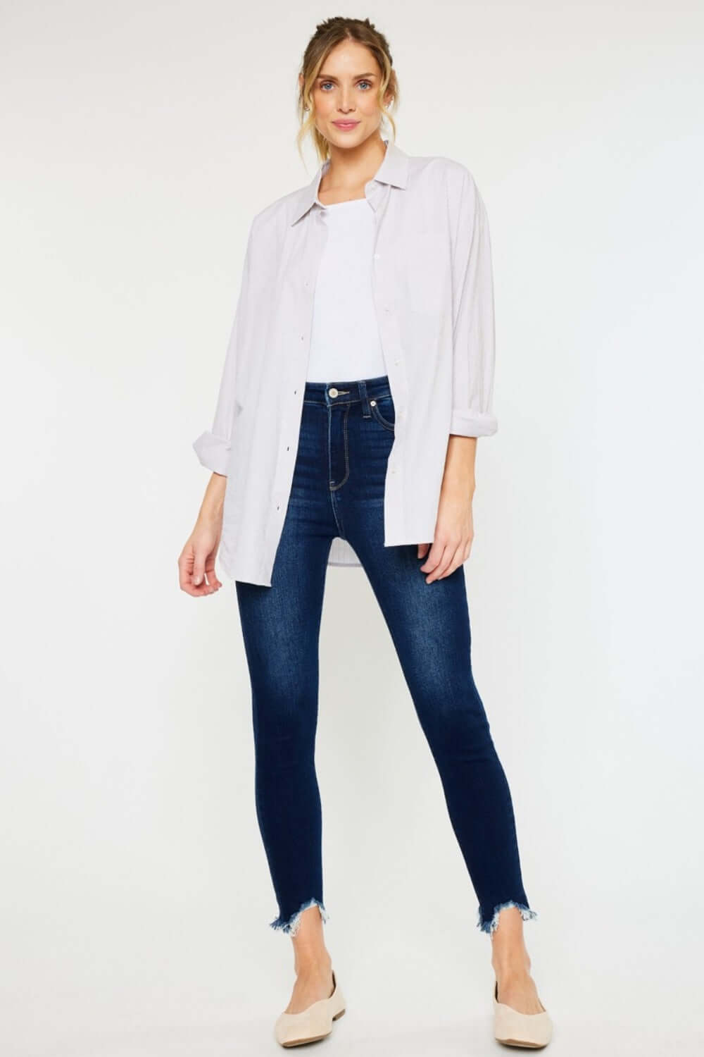 Woman wearing High Rise Frayed Ankle Skinny Jeans styled with white top and light jacket, showcasing trendy and stylish everyday look.