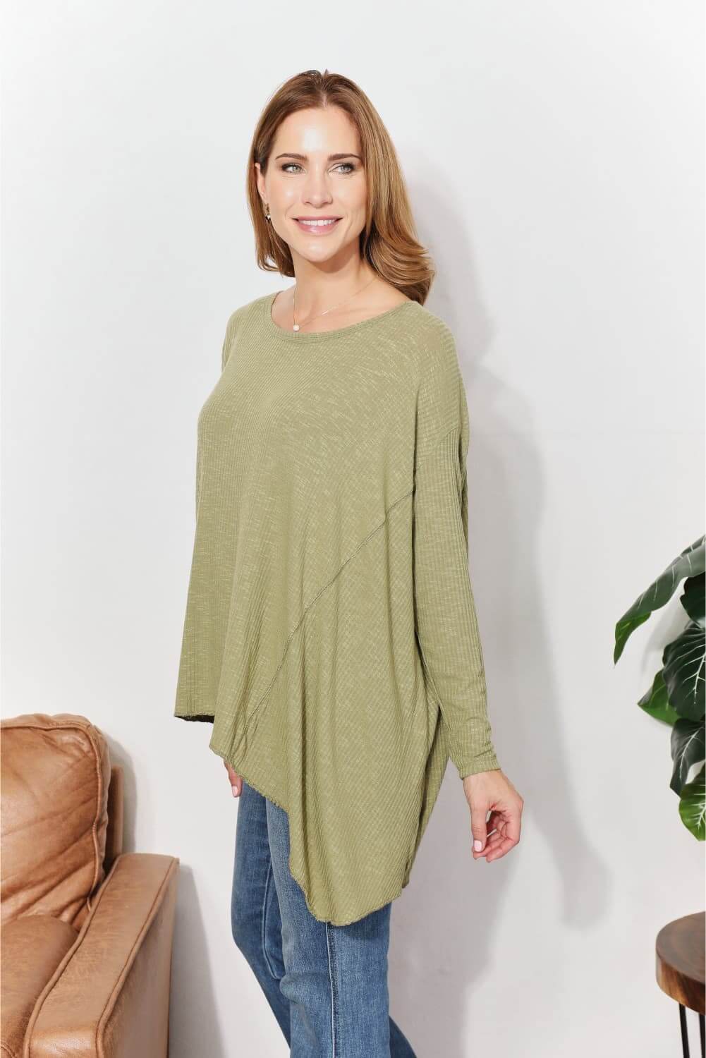 Woman wearing oversized super soft rib layering top with a sharkbite hem and round neck in a relaxed setting.