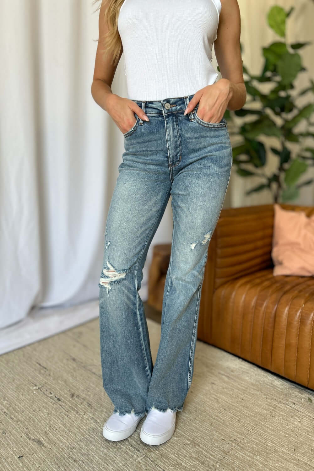 Woman wearing Judy Blue medium rise tummy control destroy flare jeans with distressed detailing in a stylish casual setting.