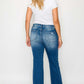 Woman wearing bytos Full Size Raw Hem Distressed High Rise Bootcut Jeans from the back, showcasing the stylish flare and raw hem.