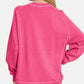 Back view of a woman wearing a pink Zenana Pigment Dyed French Terry Sweatshirt, showcasing its relaxed fit and vintage style.