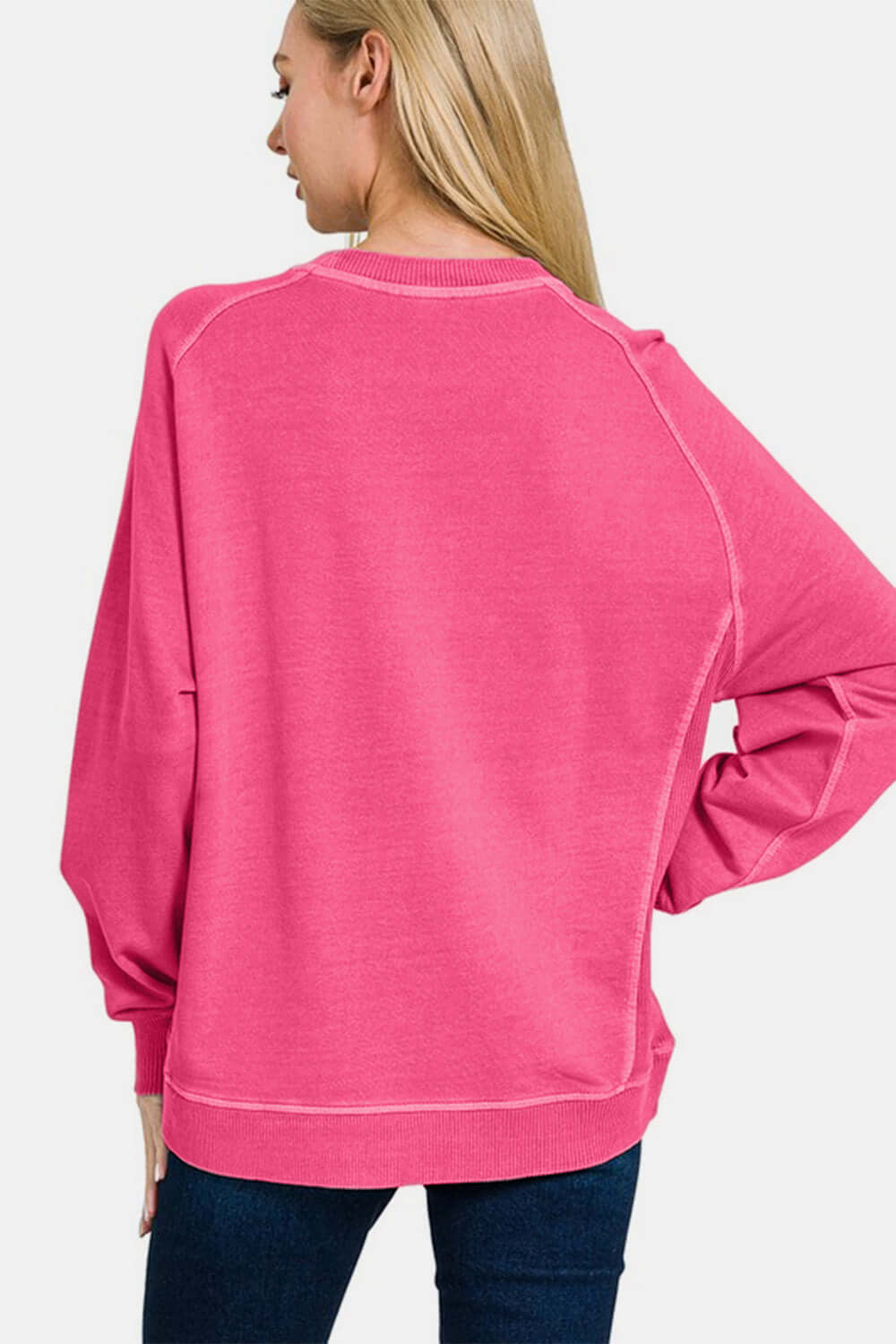 Back view of a woman wearing a pink Zenana Pigment Dyed French Terry Sweatshirt, showcasing its relaxed fit and vintage style.