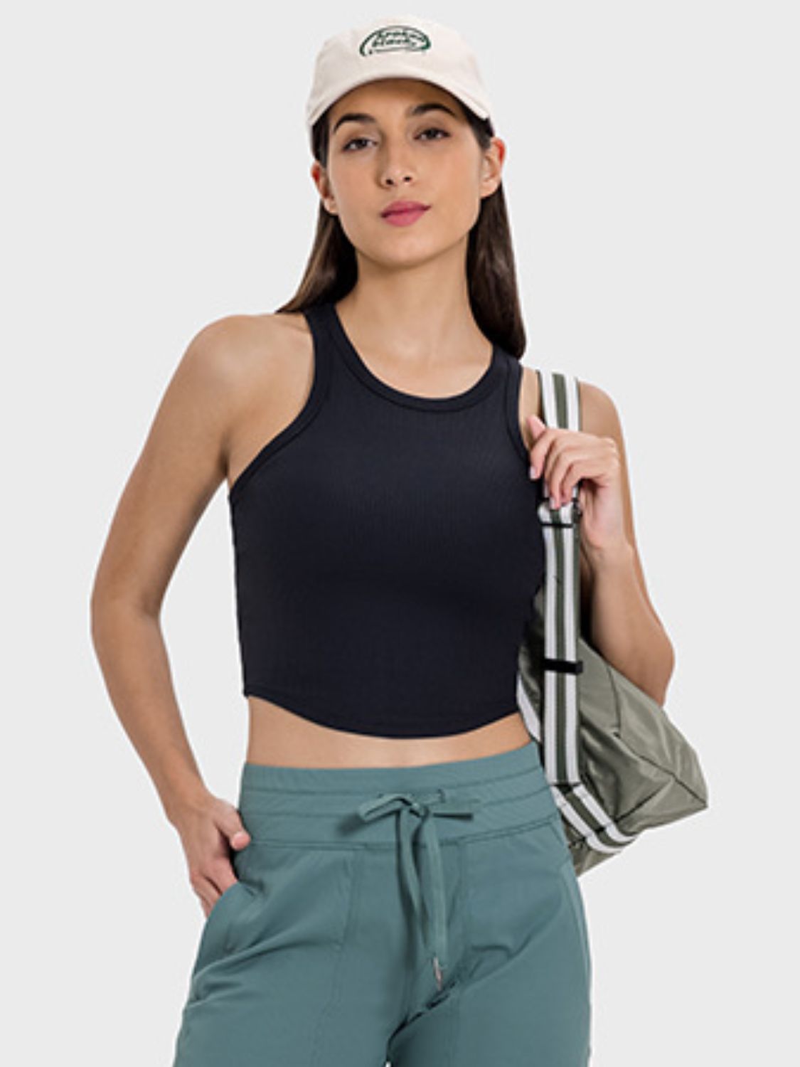 Model showcasing the Millennia Round Neck Racerback Active Tank in black, paired with cargo pants and a stylish cap.